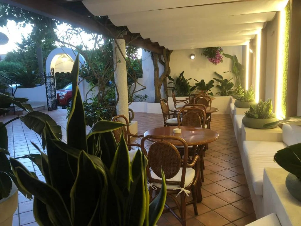 Veranda con tavoli, sedute bianche e piante verdi illuminata al tramonto