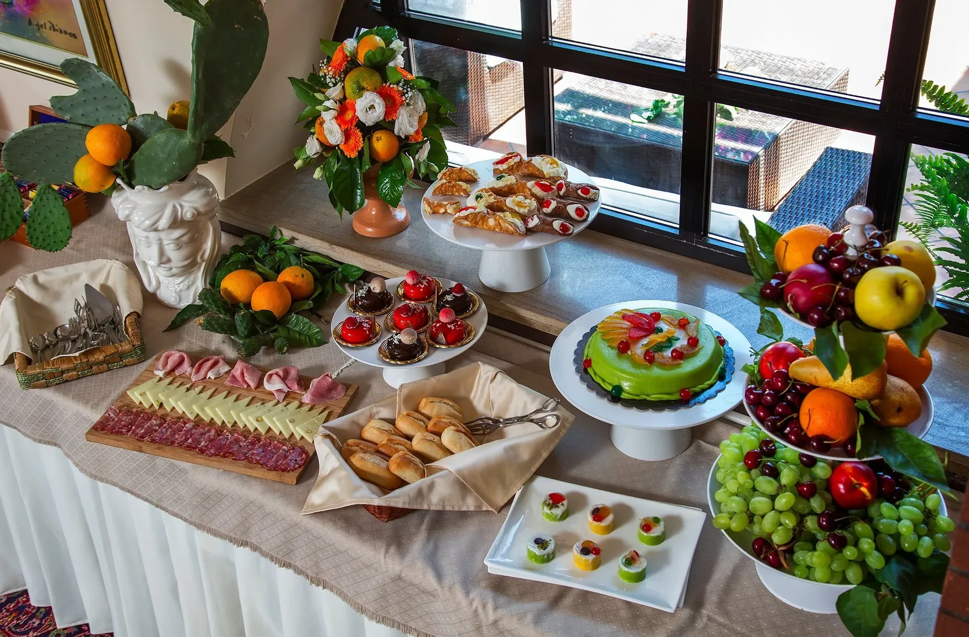 Buffet con dolci siciliani, cannoli, salumi, formaggi e frutta fresca