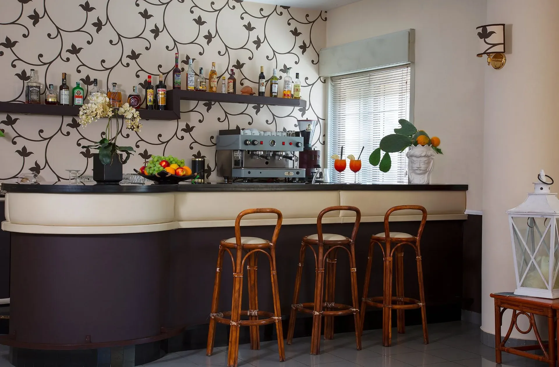 Bancone del bar con sgabelli in legno, bottiglie di liquori e cocktail