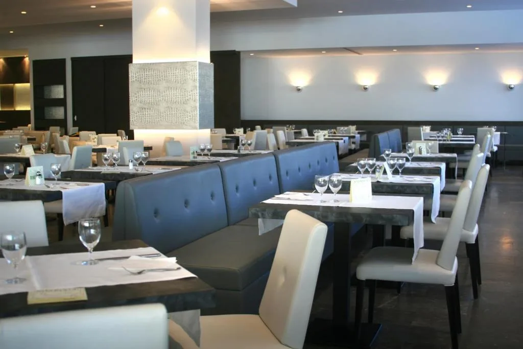 Sala ristorante moderna con tavoli apparecchiati, sedie chiare e divanetti blu