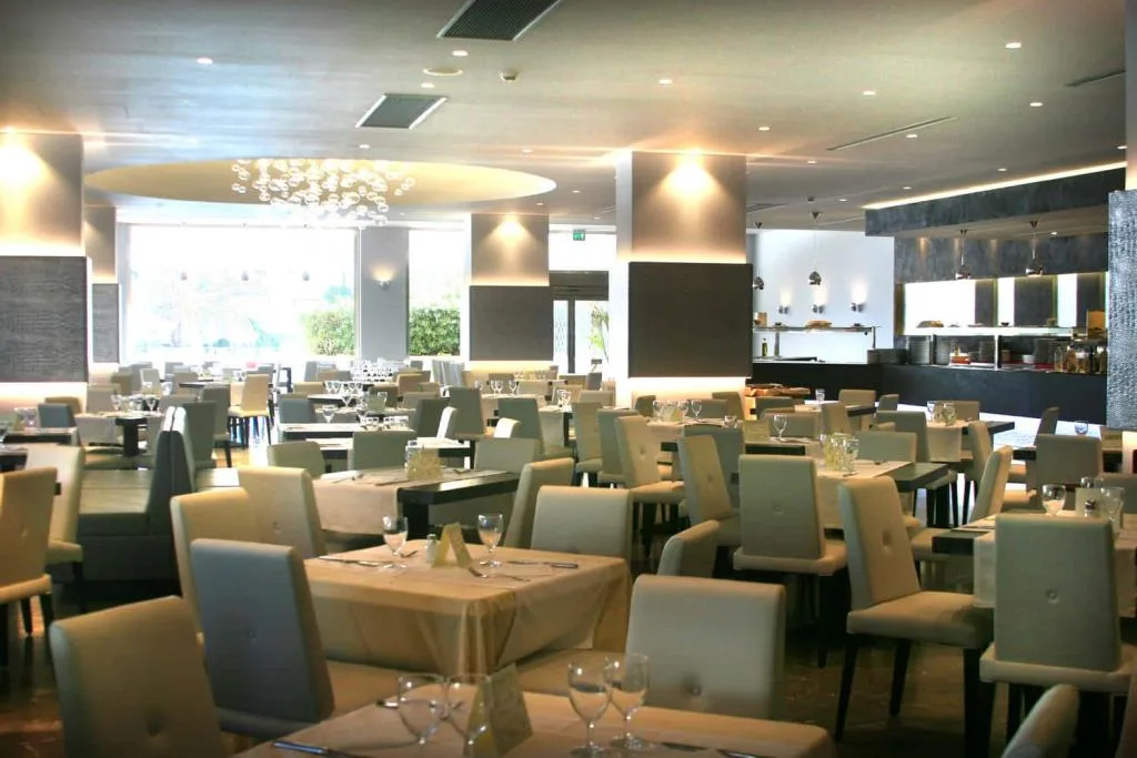 Ampia sala ristorante luminosa con numerosi tavoli apparecchiati e lampadario di design