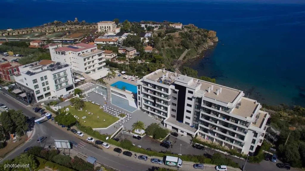 Veduta aerea dell'hotel sulla costa con piscina, giardino e mare azzurro