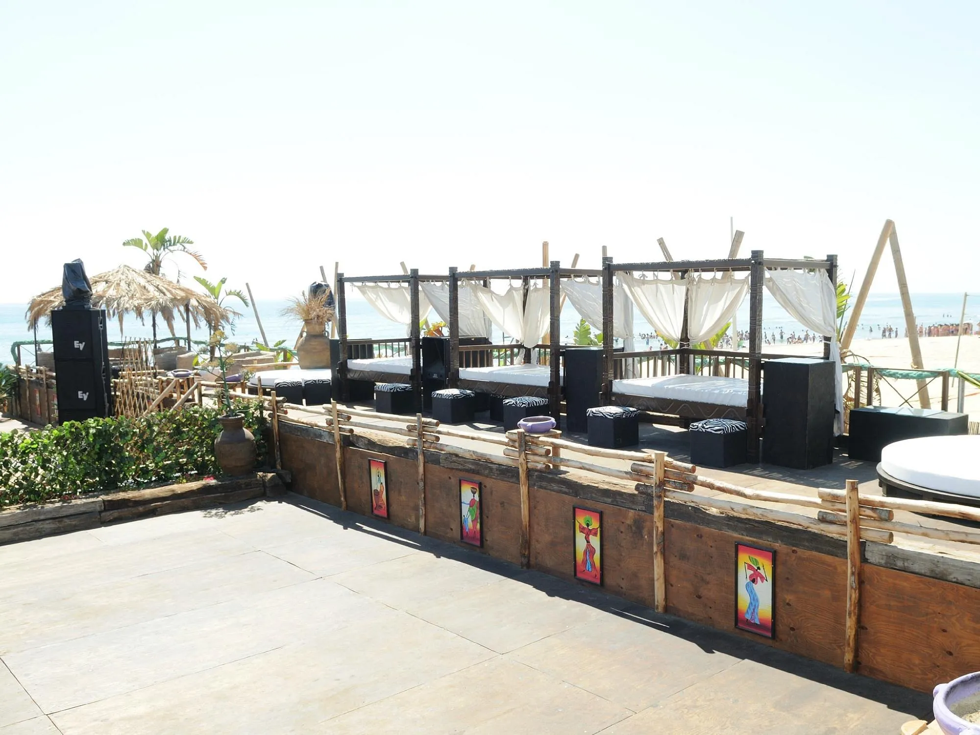 Area lounge con letti baldacchino e tende bianche vista mare in beach club