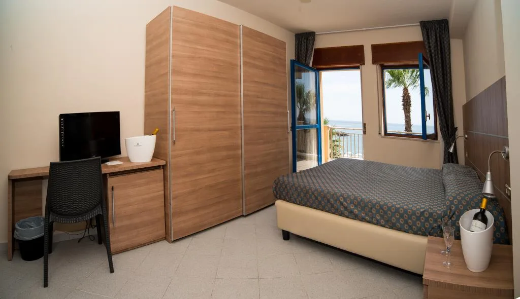 Camera con due letti, armadio in legno e balcone con vista mare
