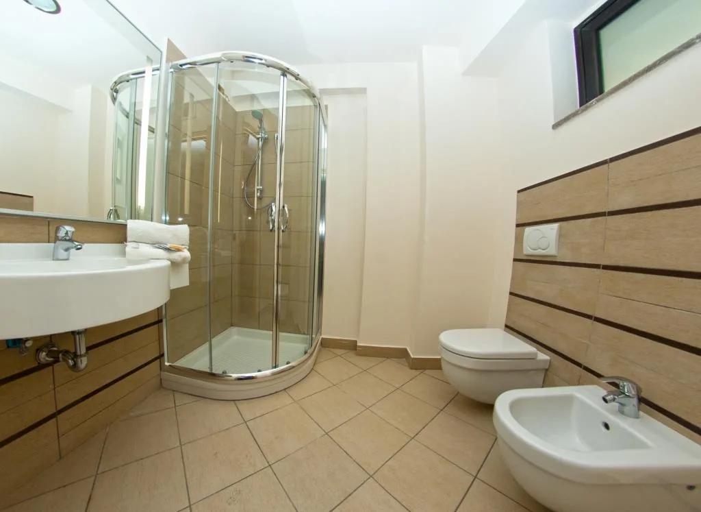 Bagno moderno con doccia in vetro, lavabo, wc e bidet con piastrelle beige