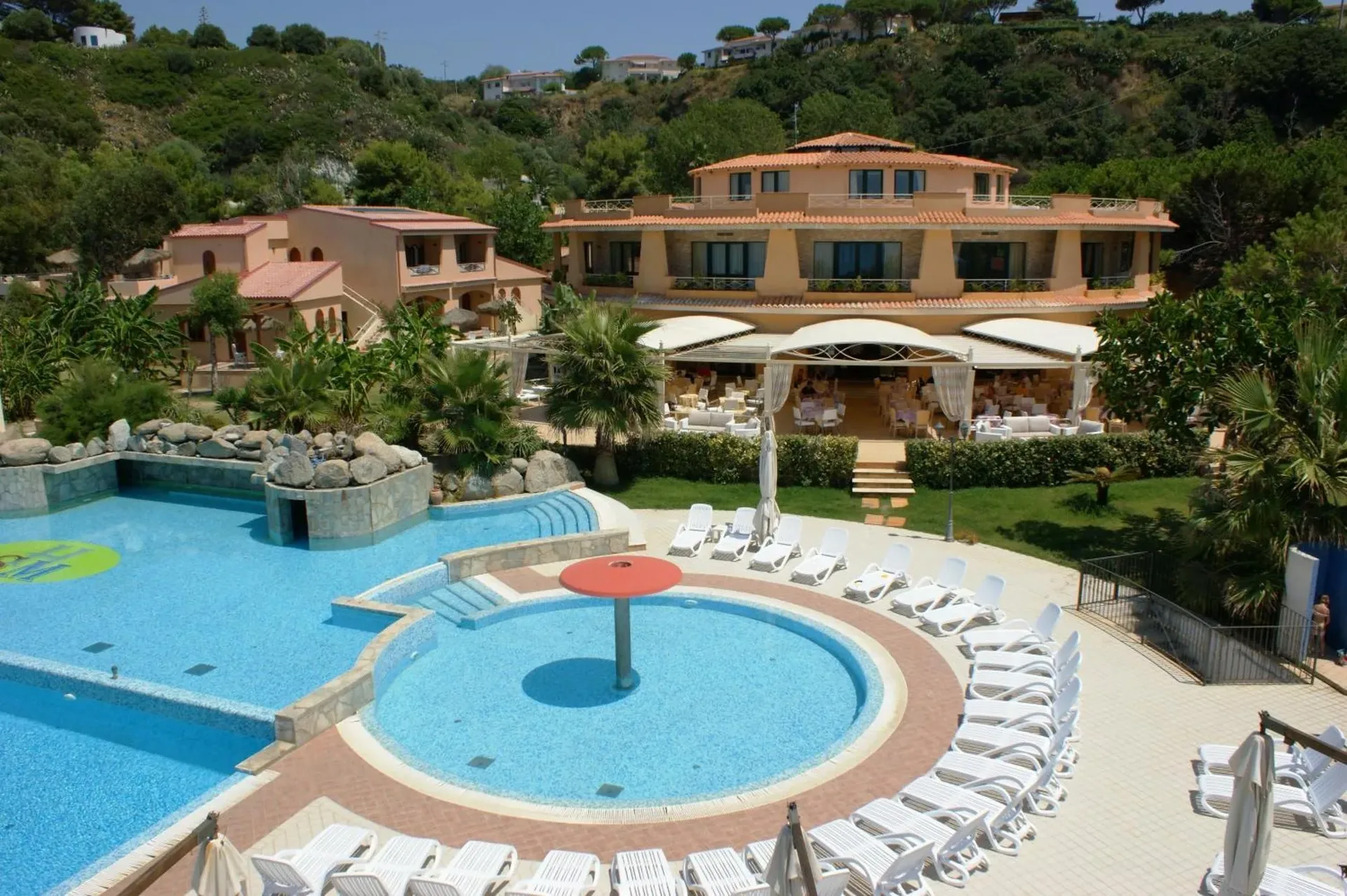 Veduta del resort con piscina, area relax e ristorante immersi nel verde