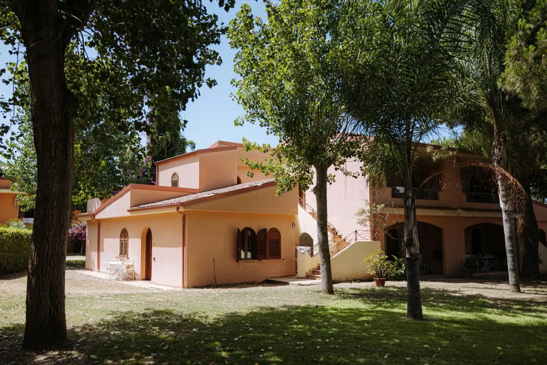 Edifici del residence in stile mediterraneo color pesca immersi nel verde