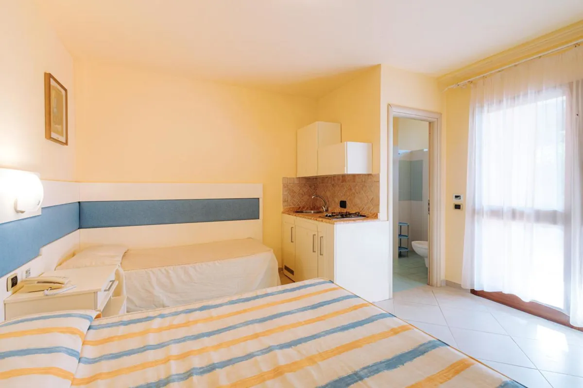 Camera con letto matrimoniale, letto singolo e angolo cottura attrezzato