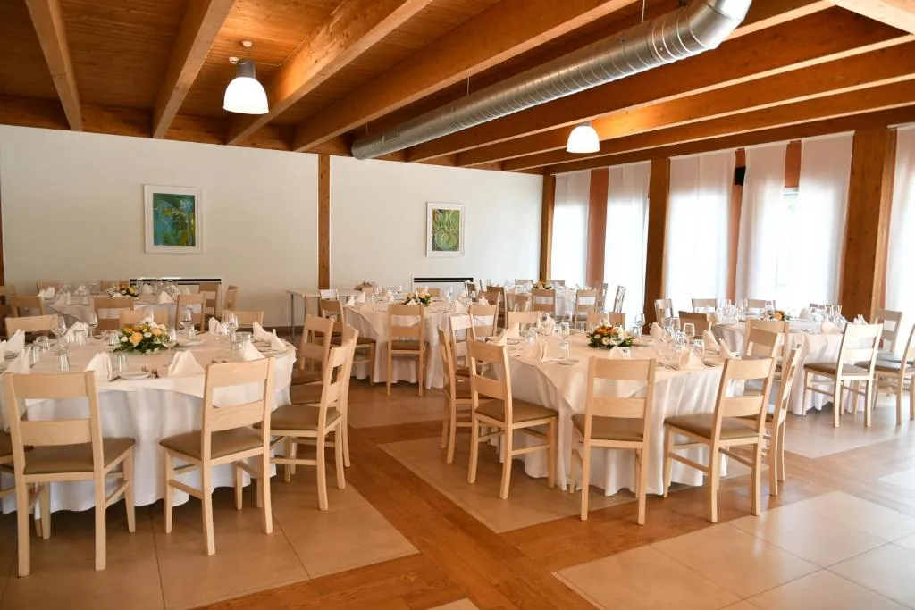 Sala ristorante con tavoli rotondi apparecchiati e soffitto in legno