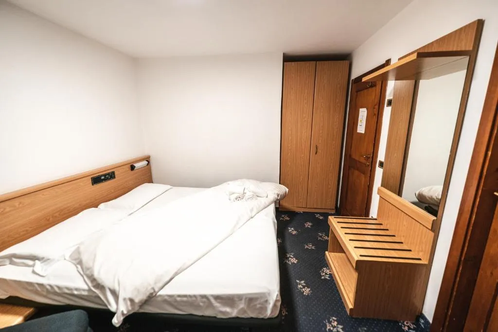 Camera doppia essenziale con letto, armadio e specchio