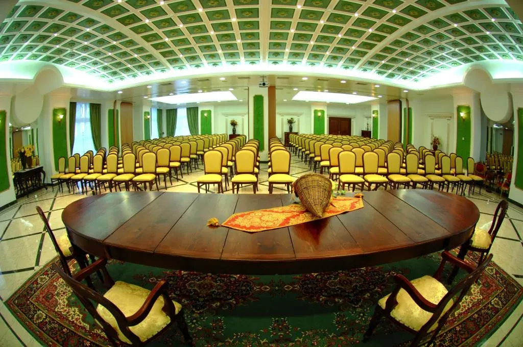 Sala congressi con sedie disposte a platea e soffitto a cassettoni verde