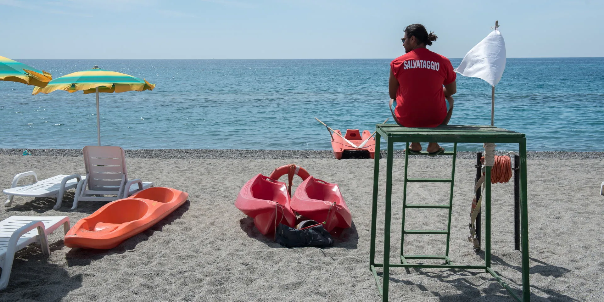 Bagnino di salvataggio in spiaggia con pattini e ombrelloni davanti al mare