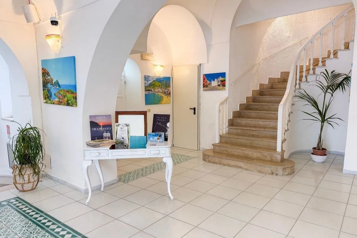 Hall dell'hotel con archi bianchi, scala e quadri panoramici