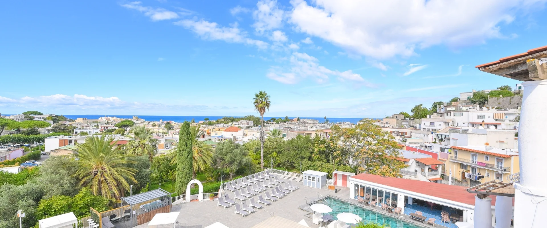 Panorama sul paese e sul mare con palme, giardino e area piscina dell'hotel