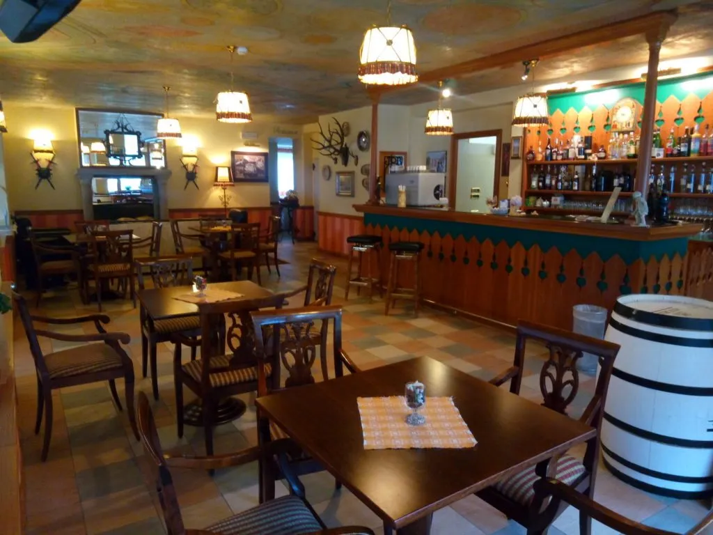 Bar dell'hotel con bancone, sgabelli, tavoli in legno e soffitto affrescato