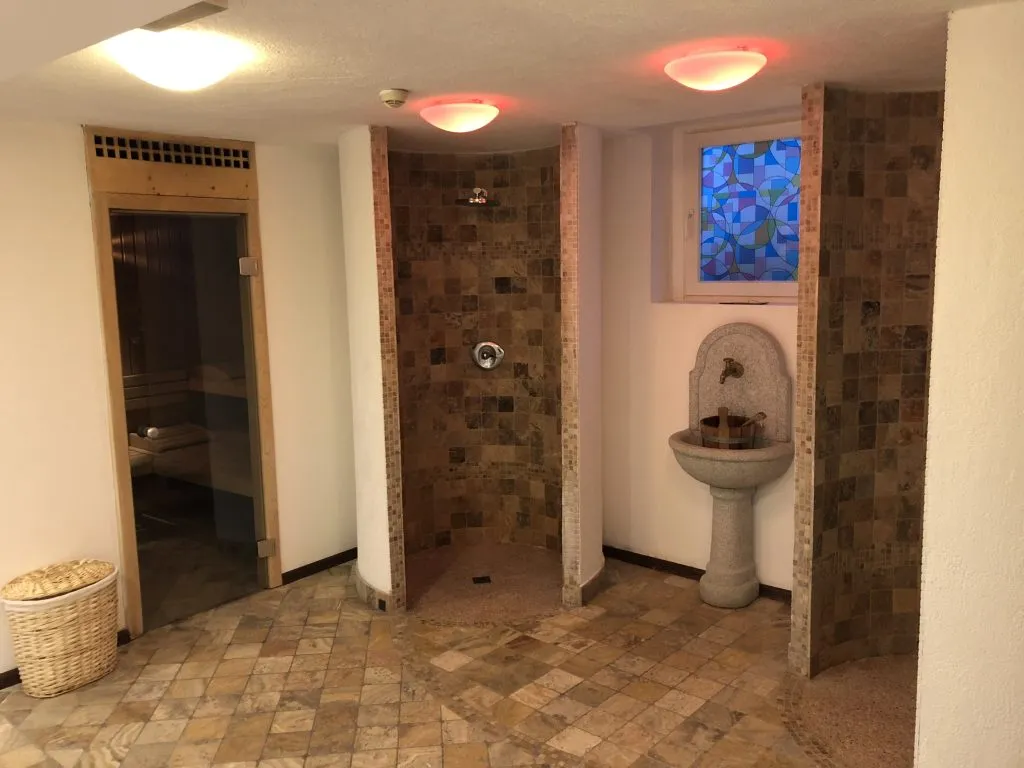 Area sauna con doccia emozionale, fontana in pietra e vetrata colorata
