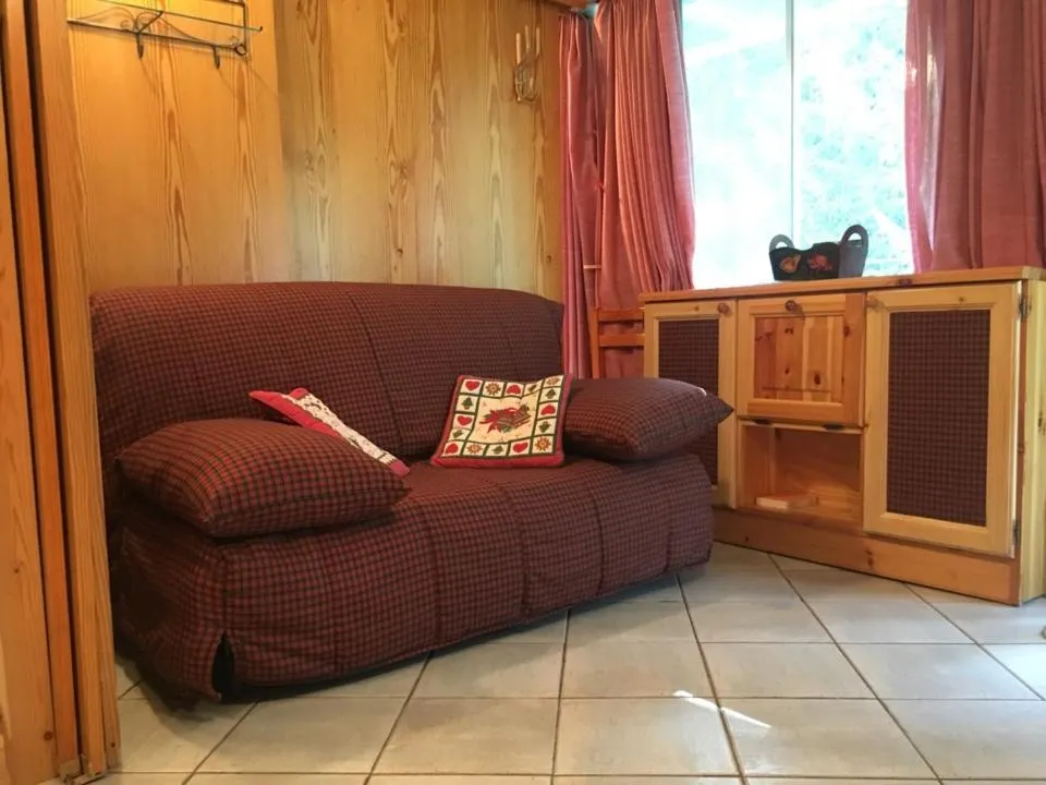 Angolo soggiorno rustico con divano a quadri rosso, cuscini decorativi e mobile in legno