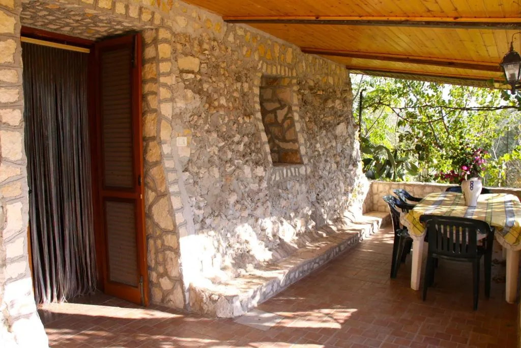Veranda esterna in pietra con tavolo e sedie affacciata sul verde