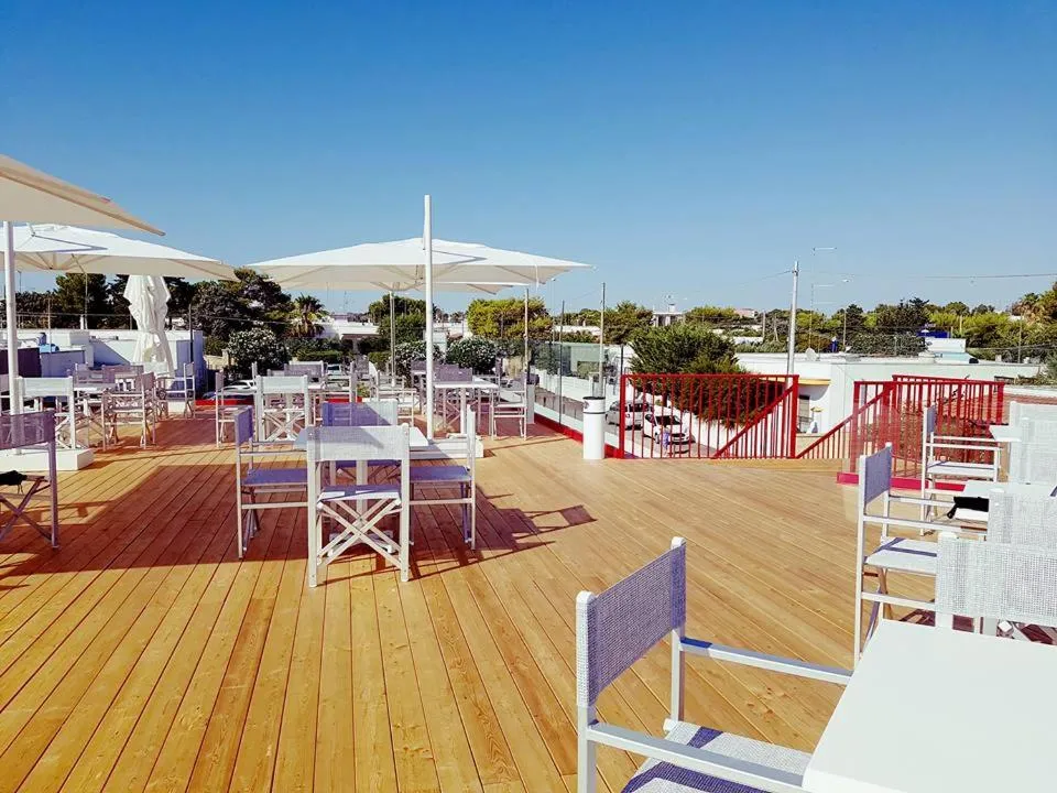 Ampia terrazza panoramica in legno con tavoli, sedie e ombrelloni bianchi