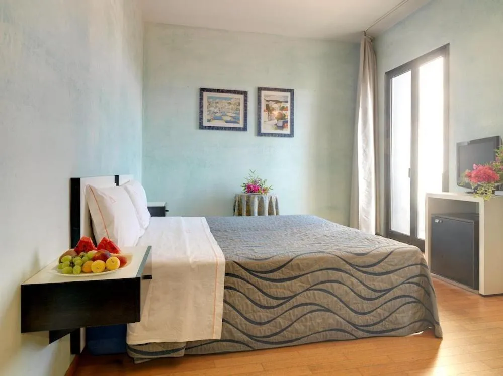 Camera con letto matrimoniale, pareti azzurre e vassoio di frutta fresca