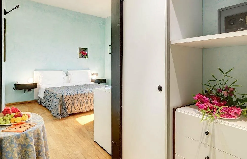Camera matrimoniale con pareti azzurre, letto e cassettiera bianca con fiori