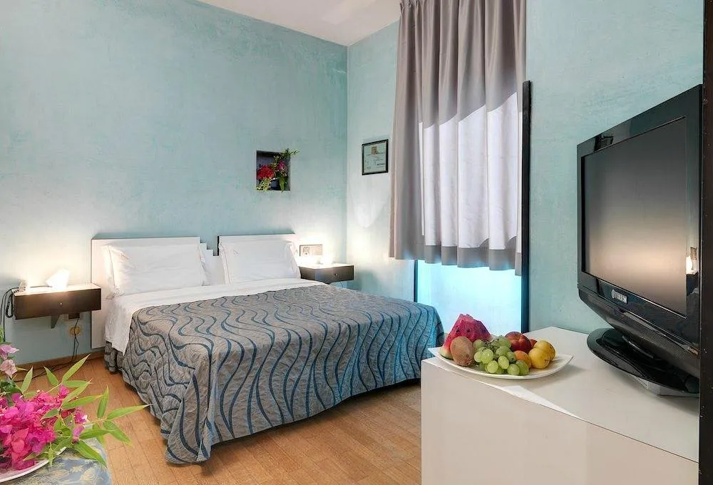 Camera da letto con pareti azzurre, letto matrimoniale, TV e piatto di frutta