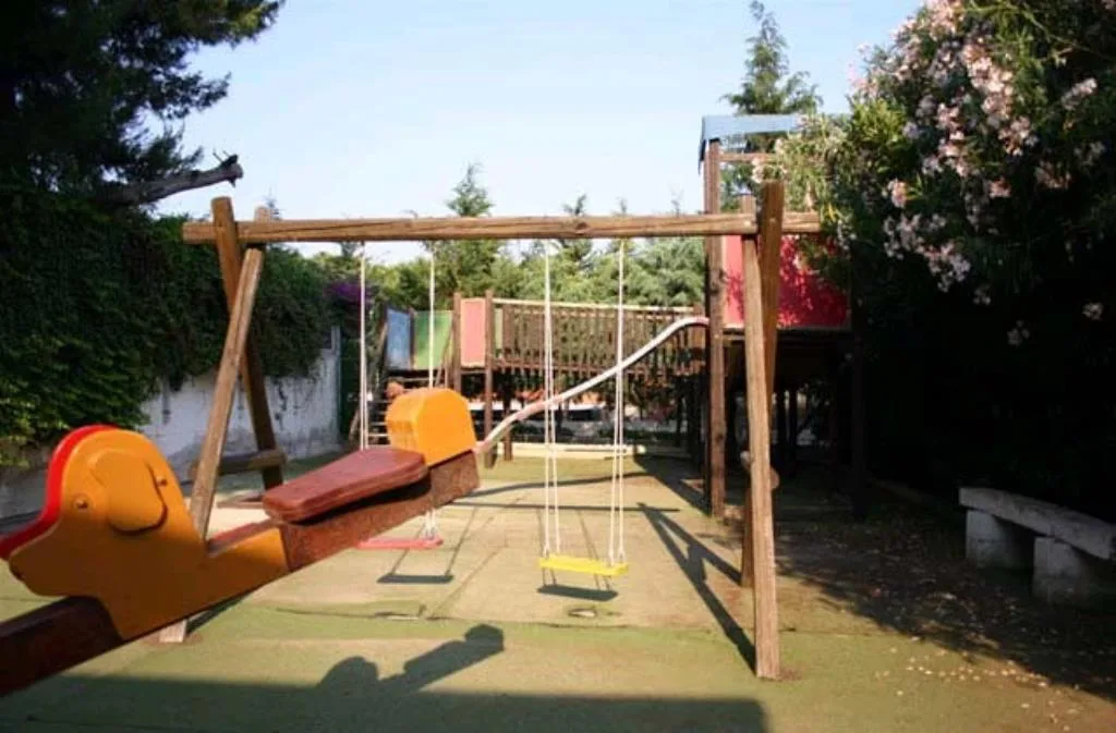 Parco giochi per bambini con altalene e dondolo nel giardino