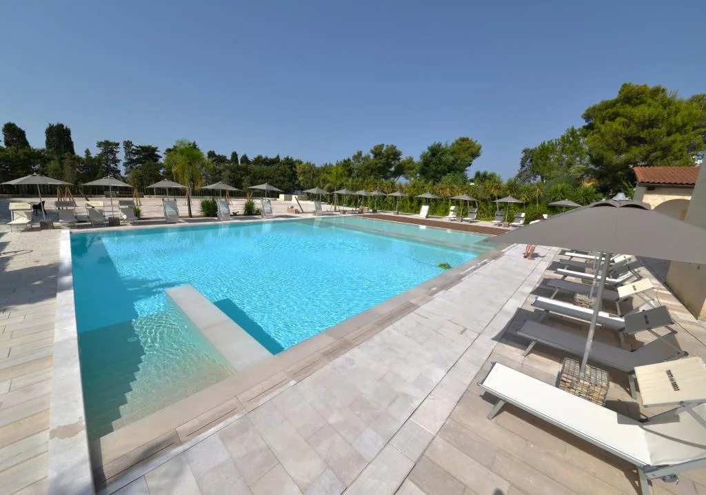 Piscina panoramica con solarium e lettini sotto ombrelloni grigi