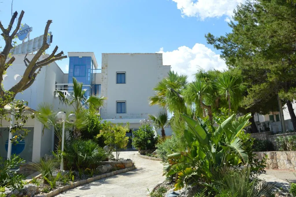 Facciata dell'edificio bianco circondata da palme e giardino tropicale