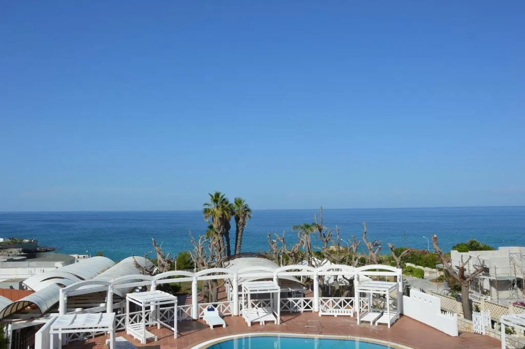 Vista panoramica sul mare con piscina e gazebo bianchi in primo piano