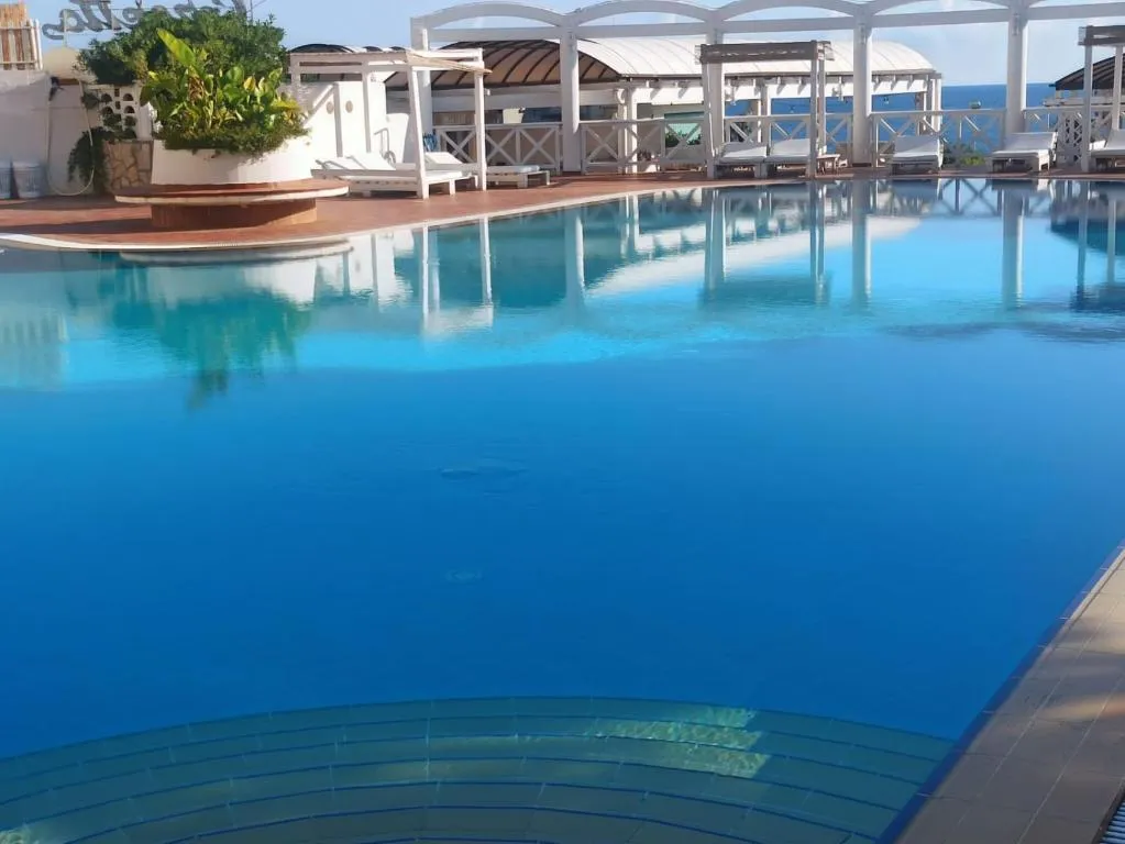 Piscina blu con scalini e gazebo bianchi affacciata sul mare