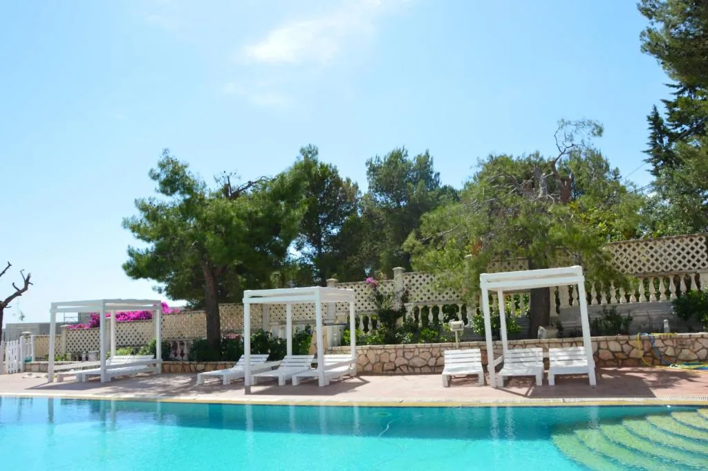 Bordo piscina con lettini bianchi e gazebo immersi nel verde
