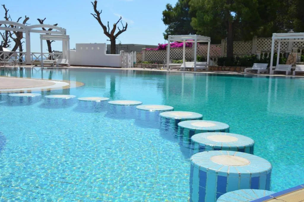 Piscina con sedute mosaicate in acqua e gazebo bianchi
