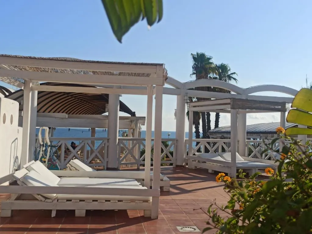 Area relax con lettini bianchi sotto gazebo affacciati sul mare