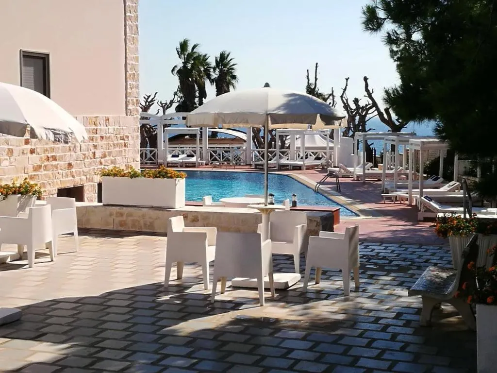 Terrazza con tavoli e poltroncine bianche a bordo piscina con vista mare