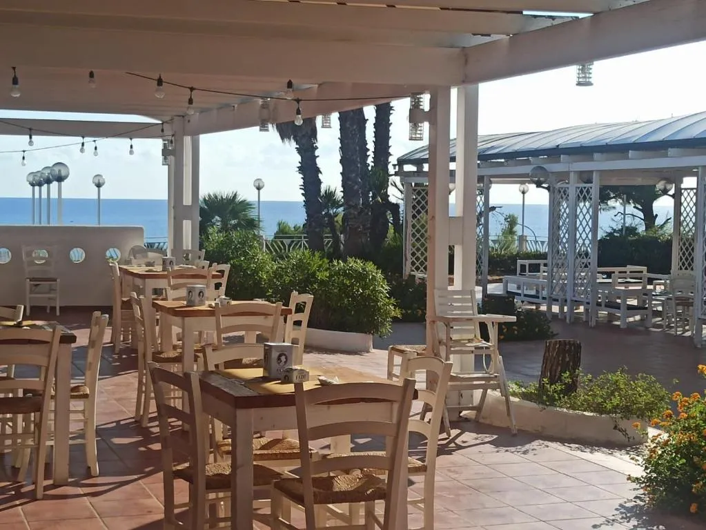Ristorante all'aperto con tavoli e sedie bianche affacciato sul mare