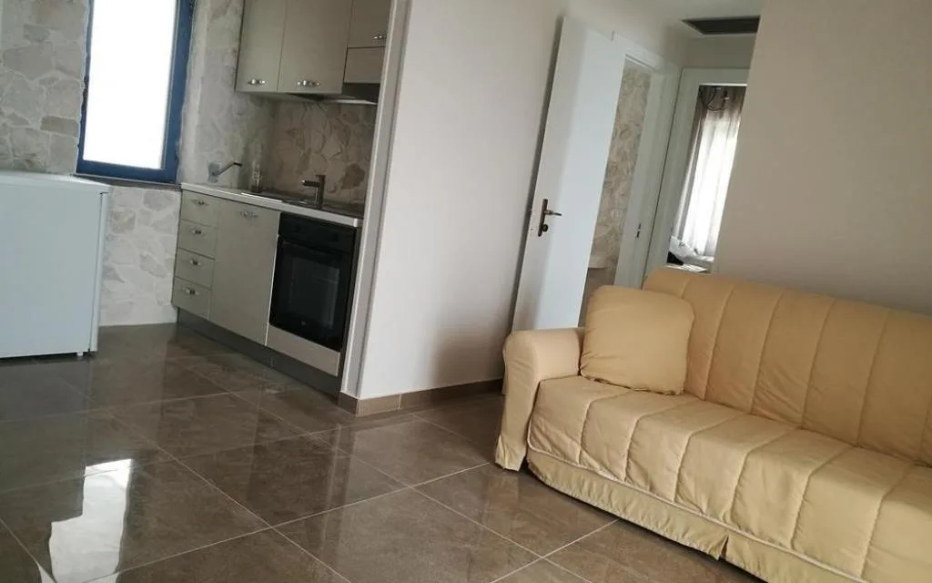 Soggiorno con angolo cottura, divano beige e pavimento lucido