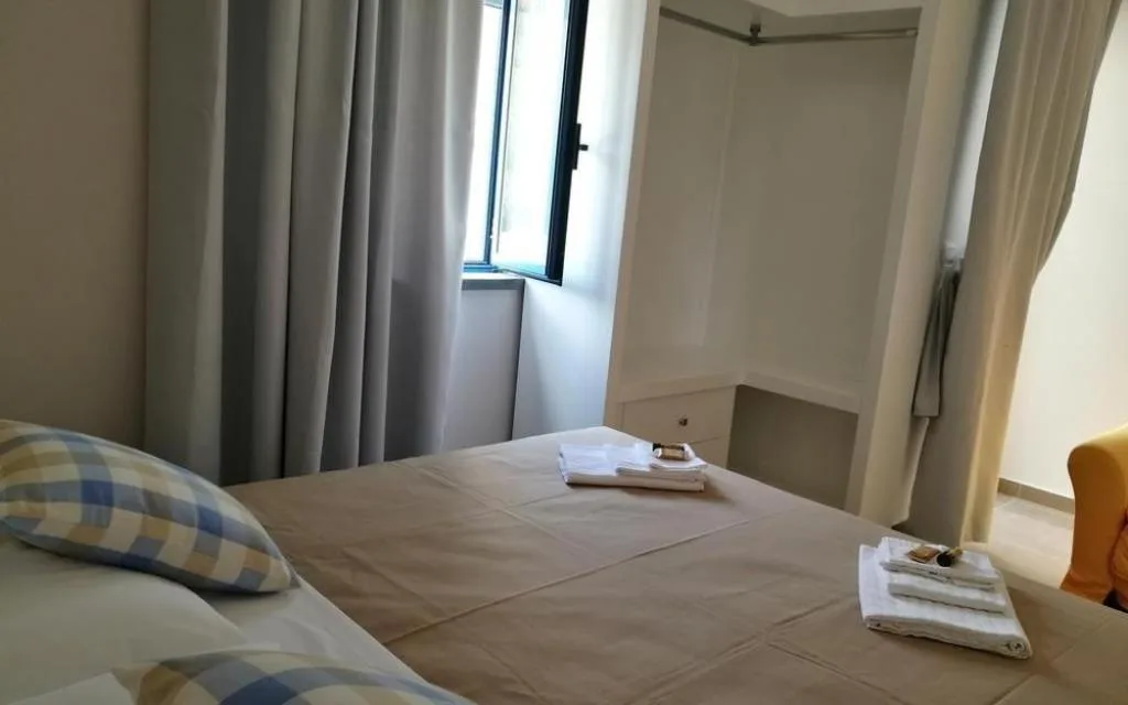 Camera con letto matrimoniale, tende grigie e finestra