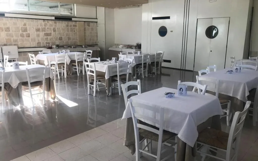 Sala ristorante interna con tavoli apparecchiati e sedie bianche