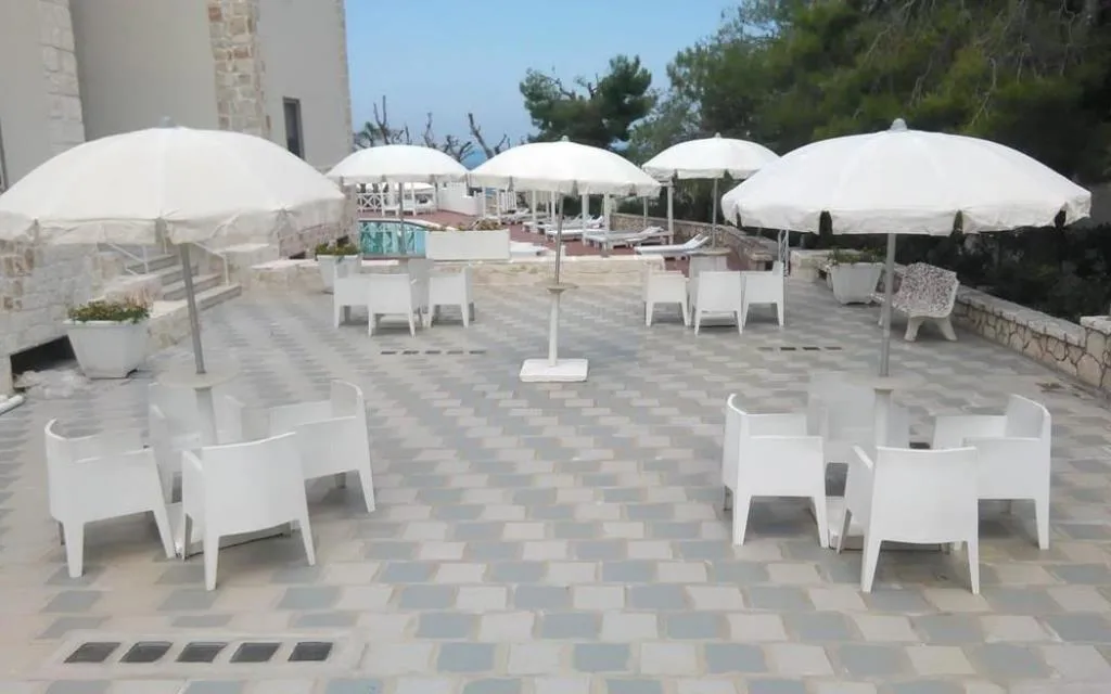 Terrazza esterna con ombrelloni bianchi, tavoli e poltroncine vista mare