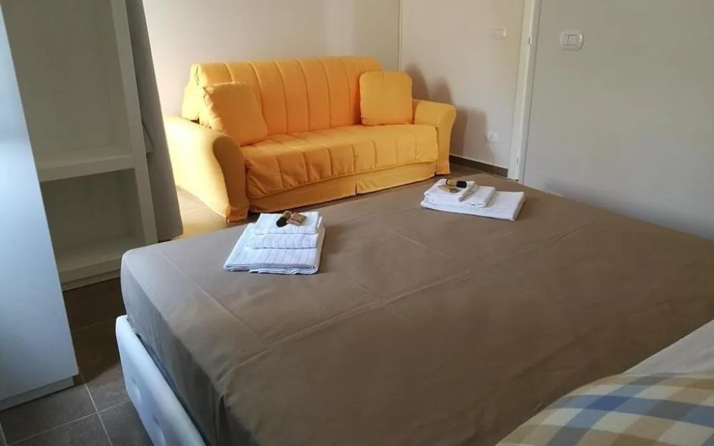 Camera con letto e divano arancione, asciugamani e kit di cortesia