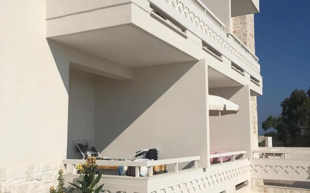 Balconi esterni dell'edificio con ringhiere bianche e ombrellone