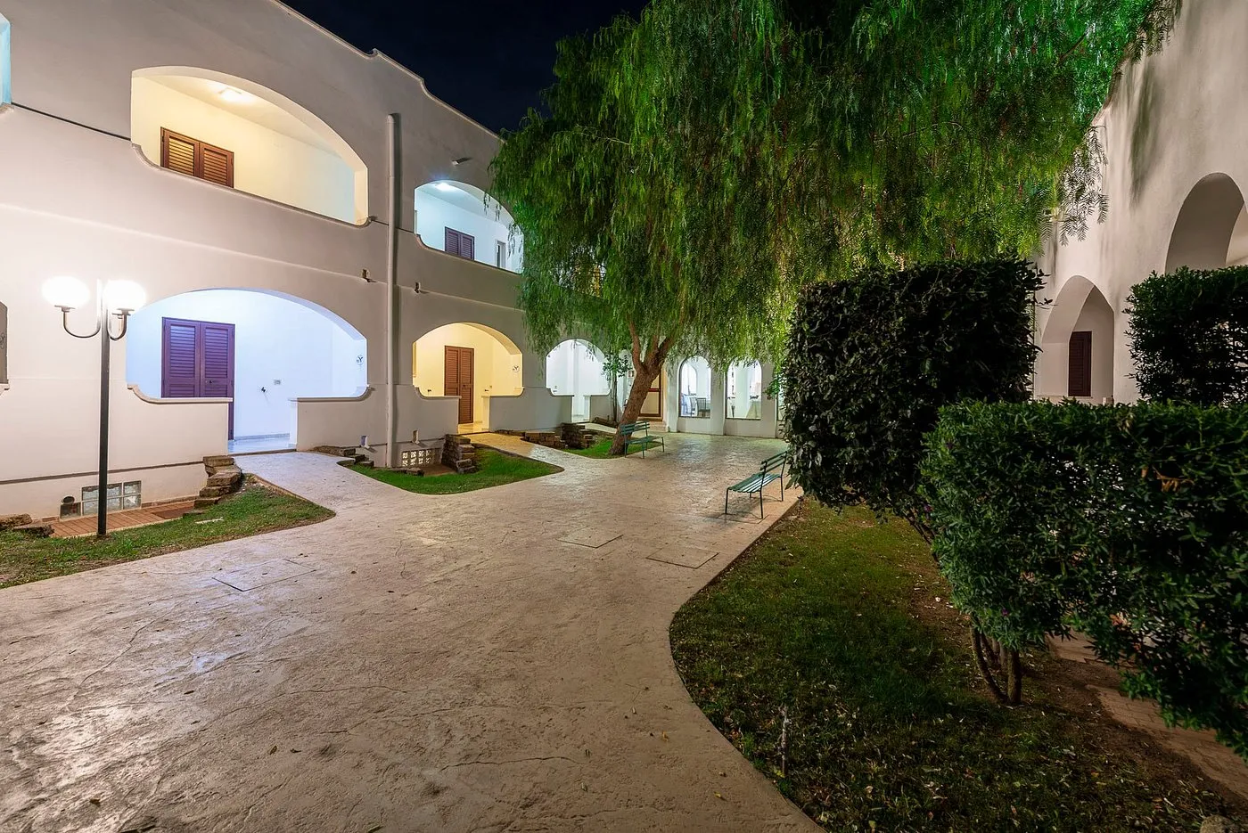 Cortile interno dell'hotel di sera con archi illuminati e albero centrale