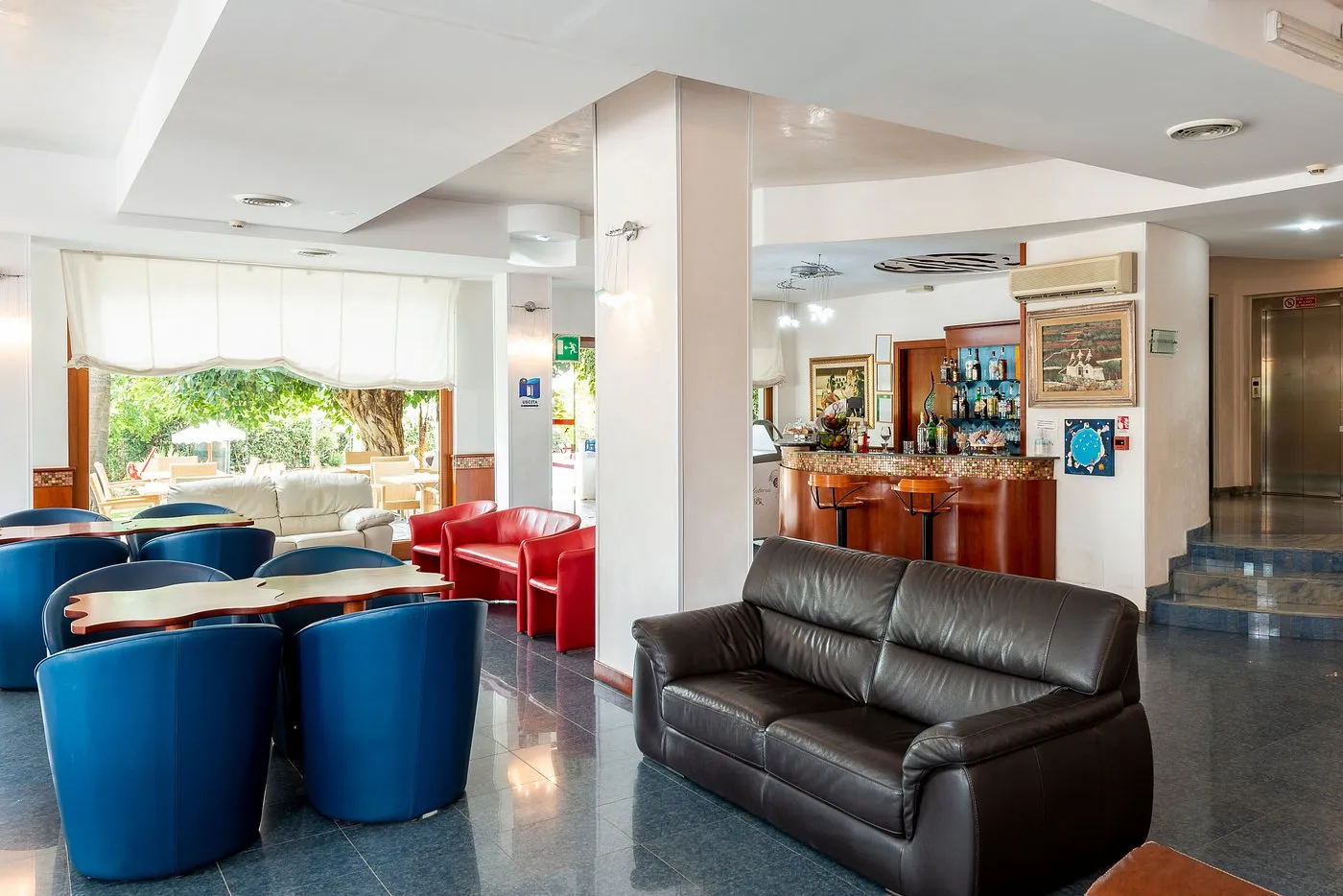 Hall dell'hotel con poltrone blu, divani in pelle e angolo bar