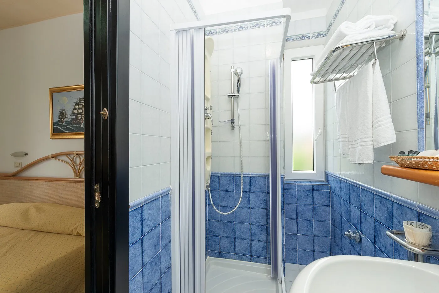 Bagno con doccia, piastrelle blu e portasciugamani con asciugamani