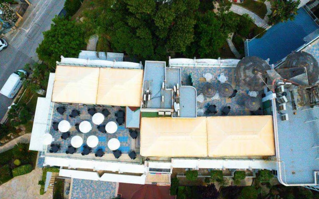 Vista aerea della terrazza dell'hotel con ombrelloni e tavoli circondata da verde