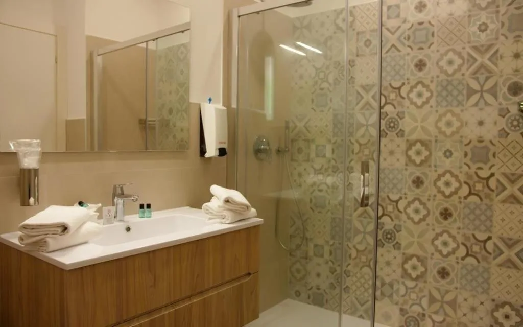 Bagno moderno con doccia in vetro, lavabo in legno e piastrelle decorative
