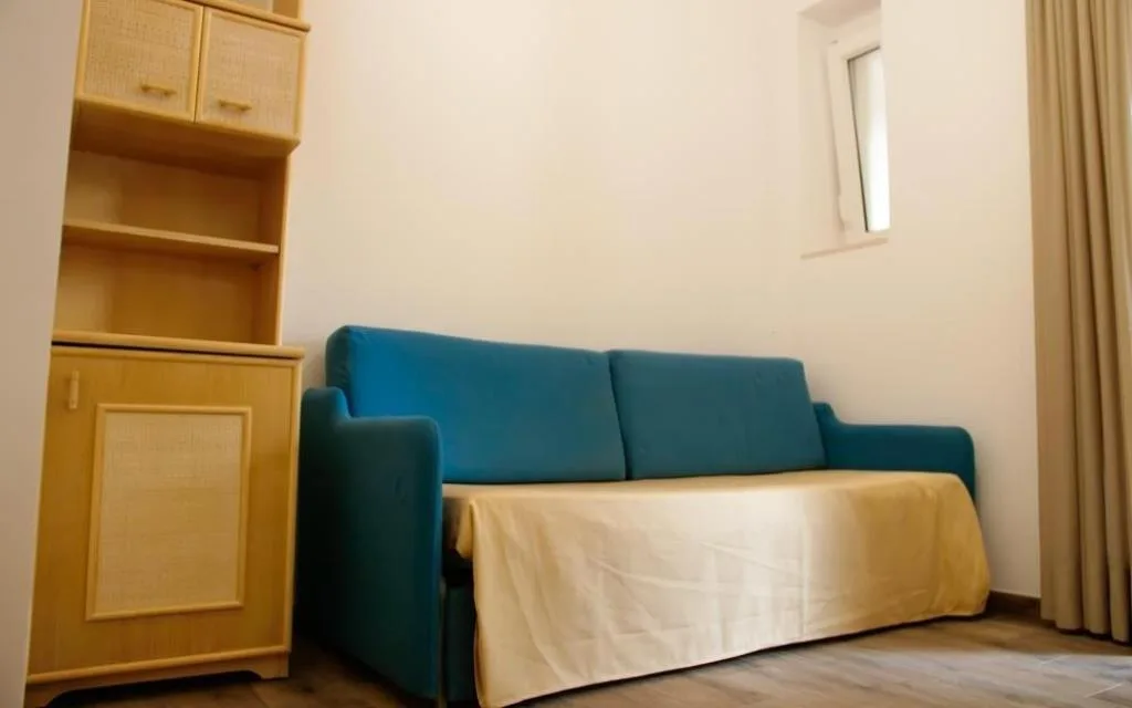 Angolo soggiorno con divano blu e mobile in vimini