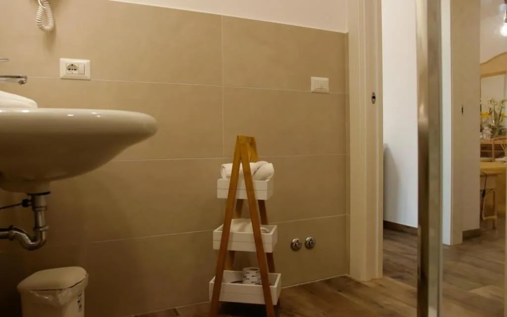 Bagno con lavabo, pareti beige e portasciugamani in legno
