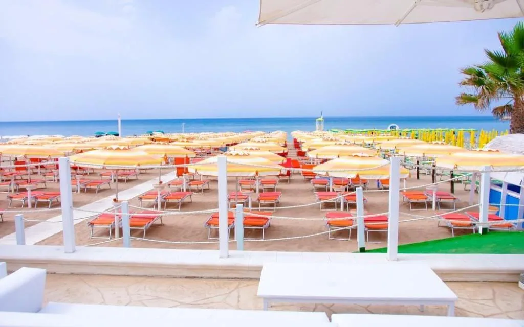 Spiaggia attrezzata con ombrelloni colorati e lettini vista mare